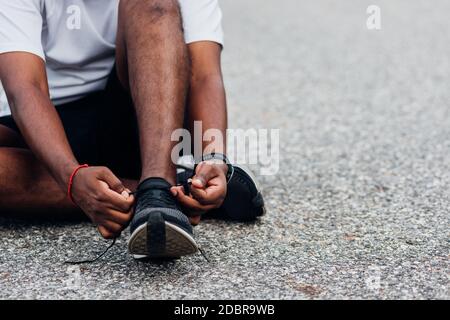 Nahaufnahme Asian Sport Läufer schwarzer Mann sitzen Schnürsenkel versuchen Laufschuhe immer bereit für Joggen und laufen auf der Straße im Freien, Gesundheit Übung w Stockfoto