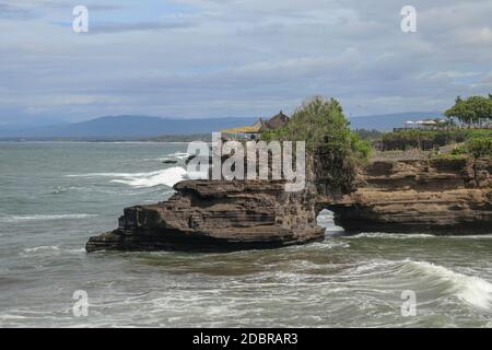 Batu Bolong Strand, der einen touristischen Anziehungspunkt nahe Tanah Lot Tempel hat. Riesiges Loch in Felsklippe unterhalb Pura Batu Bolong Tempel. Hindu-Tempel Stockfoto