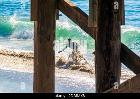 Junger Mann in Wetsuit Skimboards in der Nähe des Balboa Pier während der King Tide. Stockfoto