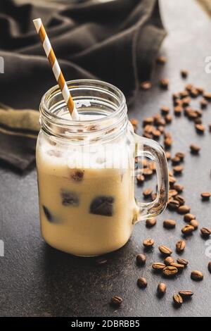Eiskaffee mit Kaffeeeiswürfeln auf schwarzem Tisch. Stockfoto