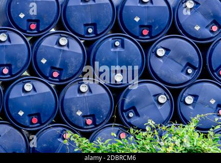 Nahaufnahme Stapel von chemischen Fässern. Blaue Ölfass. Kunststofföltank. Lager für giftige Abfälle. Gefahr Chemikalienfass mit Warnschild. Industrieabfälle Stockfoto