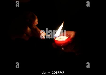 Beleuchtung einer Devotionenkerze in einer Kirche Stockfoto