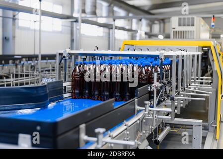 Automatische Linie für Vakuumverpackungen in einer Brauerei. Braune Kunststoffflaschen auf dem Förderband Stockfoto