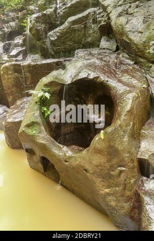 Die Erosion schuf ein Loch in Form eines Herzens im Felsen. Eine herzförmige Lücke im Stein eines Flussbettes in Bali, Indonesien. Stockfoto