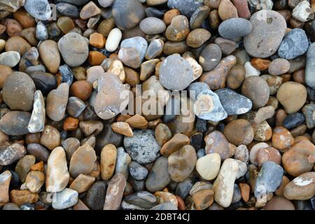 Kieselsteine verschiedener Felsen in verschiedenen Formen, Größen und Farben von einem Strand, der als Hintergrund verwendet werden könnte. Stockfoto