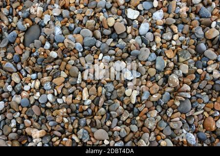 Kieselsteine verschiedener Felsen in verschiedenen Formen, Größen und Farben von einem Strand, der als Hintergrund verwendet werden könnte. Stockfoto