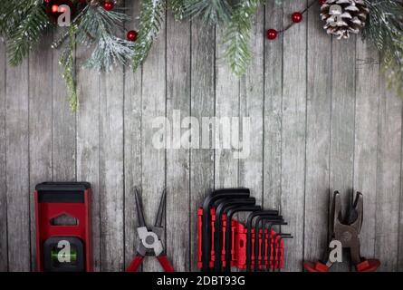 Herrenwerkzeuge liegen auf einem hölzernen Weihnachtshintergrund und einem Geschmückter Weihnachtsbaum-Zweig liegt oben Stockfoto