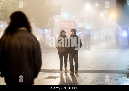 Madrid, Spanien. November 2020. Ein Paar mit Gesichtsmasken geht auf der Straße inmitten von dichtem Nebel. Die spanische Staatliche Meteorologische Agentur (AEMET für seine Abkürzung auf Spanisch) hat für diesen Mittwoch in der Gemeinschaft von Madrid eine gelbe Warnung für intensive Nebelbänke angekündigt. Kredit: SOPA Images Limited/Alamy Live Nachrichten Stockfoto