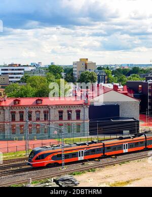 Stadtbild des Industriegebiets von Tallinn, Schnellzug auf der Eisenbahn, moderne Stadtarchitektur unter übergiebeltem Himmel mit schweren Wolken, Estland Stockfoto