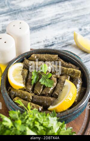 Dolma - gefüllte griechische Weinblätter (Dolmades) auf blauem Holzhintergrund Stockfoto