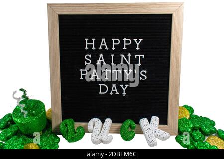 Ein schwarzes Schild mit einem Birkenrahmen, der Happy Saint Patty's Day in weißen Buchstaben mit glitzerndem, mit vier Blatt bedeckten Glovers und dem Wort Glück buchstabierte Ou sagt Stockfoto