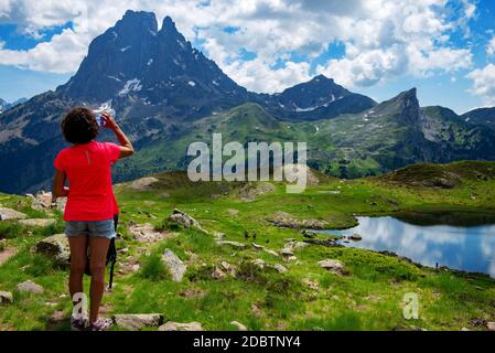 Wanderfrau trinkt ein Wasser und schaut Pic du Midi Ossau in französisch Pyrenäen Berge Stockfoto