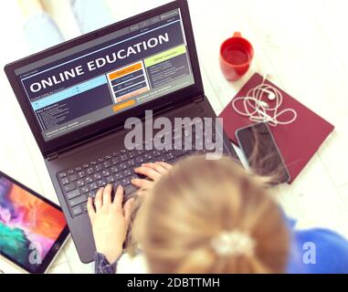 Online-Schulungen. Junge Frau schreibt einen Text auf Notebook-Tastatur mit Open Educational Web Page, während Sie Freizeit zu Hause haben. Selbstentwicklung Stockfoto