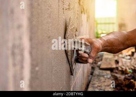 Nahaufnahme der Arbeiter mit Gipskelle, um die Wände für Hausbau, Arbeitsideen und Wohnungsbau zu putzen. Stockfoto