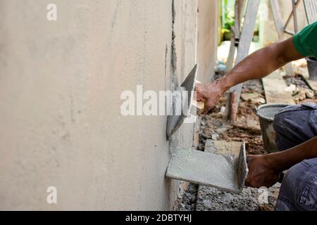 Nahaufnahme der Arbeiter mit Gipskelle, um die Wände für Hausbau, Arbeitsideen und Wohnungsbau zu putzen. Stockfoto