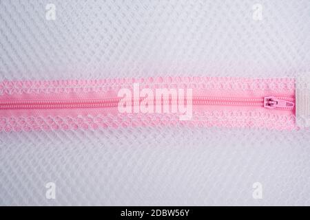 Pinkfarbener Plastikreißverschluss auf der Wäschetasche, Vollformat, Nahaufnahme Stockfoto