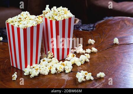 Popcorn in gestreifter retro rot-weißer Kartonschachtel für Kino auf Holztisch Stockfoto