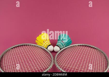 Badminton Schläger und bunt gefiederte Schuttlecken in Blau und Gelb auf pinkfarbenem Hintergrund Stockfoto