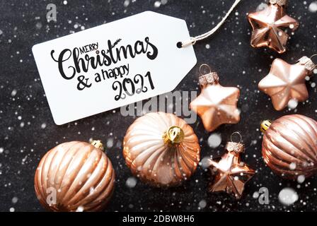 Ein Label mit englischer Kalligraphie Frohe Weihnachten und EIN glückliches 2021. Goldene Weihnachtskugel Ornament Auf Schwarzem Hintergrund Und Schneeflocken Stockfoto