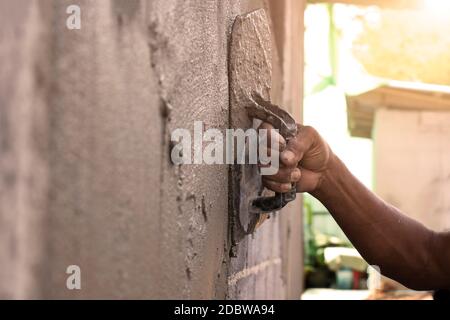 Nahaufnahme der Arbeiter mit Gipskelle für die Verputzung für den Hausbau. Konzepte der Hauserweiterung. Stockfoto