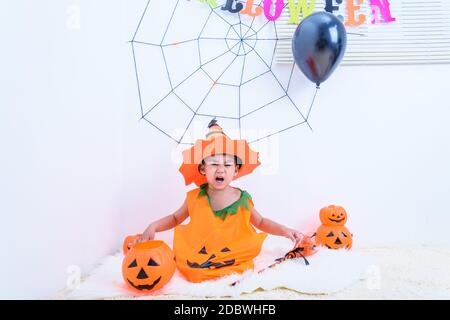 Der kleine niedliche Junge Kid auf Halloween Kostüm orange Kürbis sitzt er im Halloween Partyhaus und offenen Mund für Horror, Happy Halloween Tageskonzept Stockfoto