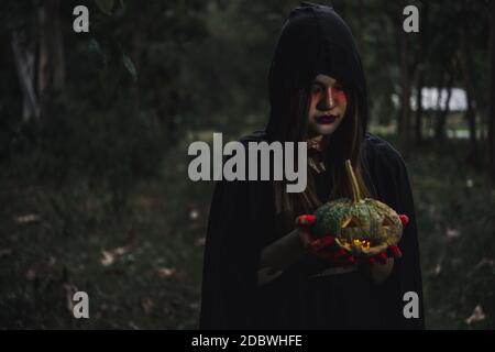 Frau Teufel Geist Dämon Kostüm Horror und beängstigend Sie hält Kürbis an der Hand im Wald. Die Vampir Geister Menschen, Happy Halloween Tag Konzept Stockfoto