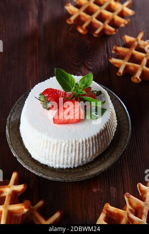 Weicher Ricotta-Käse mit Erdbeeren, Basilikumblättern und Waffeln auf dunklem Hintergrund. Das Konzept eines gesunden Frühstücks. Natürliche biologische Produkte. Stockfoto