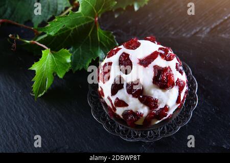 Weicher Dessertkäse mit Preiselbeeren und Traubenblättern auf schwarzem Hintergrund. Süßer Käse zum Frühstück. Köstliches Dessert. Speicherplatz kopieren. Draufsicht. Stockfoto