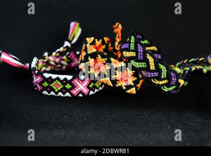 Selektive Fokus von gewebten DIY Freundschaft Armbänder handgefertigt von Stickerei hellen Faden mit Knoten auf schwarzem Hintergrund. Stockfoto