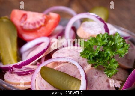 bayerischer Wurstsalat auf dunklem Holz Stockfoto