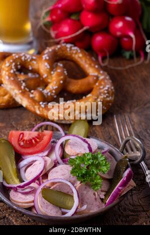 bayerischer Wurstsalat auf dunklem Holz Stockfoto