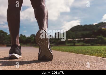Asiatische junge Athlet Sport Läufer schwarz Mann tragen Füße aktiv bereit zum Lauftraining im Freien auf dem Laufband Linie Straße für einen Schritt nach vorne, er Stockfoto