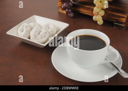 Eine Tasse Kaffee mit Puderzucker überzogenen Kuchendonuts Stockfoto