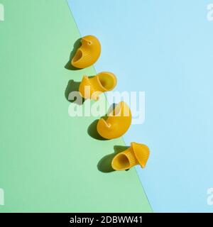 Pasta Kunst. Pipe rigate auf blau und grün duotone Pastell Hintergrund in hartem Licht. Kreatives Layout mit Pastapfeife Rigate, Draufsicht oder Flat Lay. Kreati Stockfoto