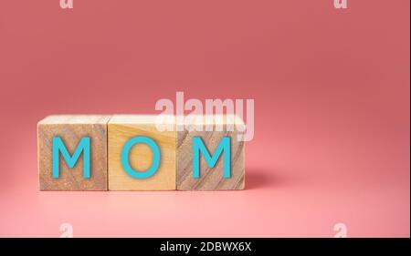 MOM Wort in Holzwürfel auf rosa Hintergrund geschrieben. Muttertagskonzept. Stockfoto