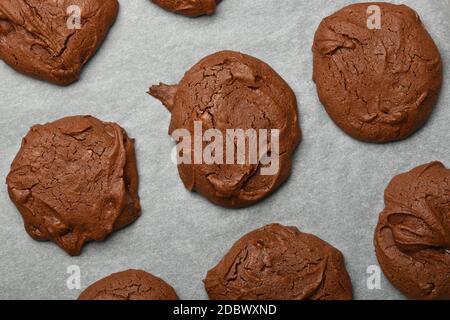 Nahaufnahme mehrere frisch gebackene runde Brownie-Schokoladenkekse auf Backpapier, erhöhte Draufsicht, direkt darüber Stockfoto