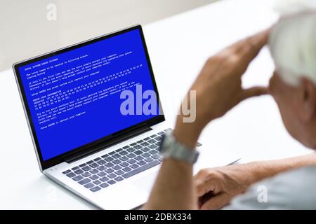 Senior mit BSOD Death Screen auf einem gehackten Laptop Stockfoto