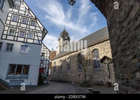 Blick durch einen Torbogen bei einem Fachwerkhaus und einer Kirche in Monschau, Deutschland Stockfoto