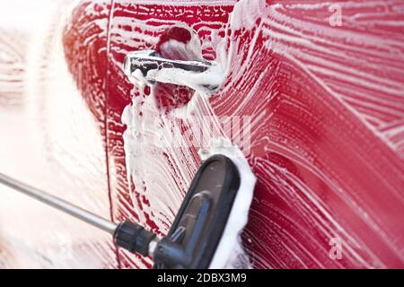 Rotes Auto gewaschen in selbst dienen Autowäsche, Detail auf Pinsel verlassen Striche auf Seitentür, breites Banner mit leerem Raum für Text linke Seite. Stockfoto