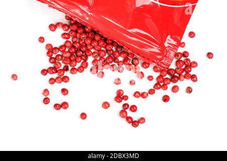 Rosa Pfefferkörner - getrocknete Früchte aus peruanischem peppertree Schinus molle, mit roter Plastikverpackung in der Nähe, Nahaufnahme Detail von oben. Stockfoto