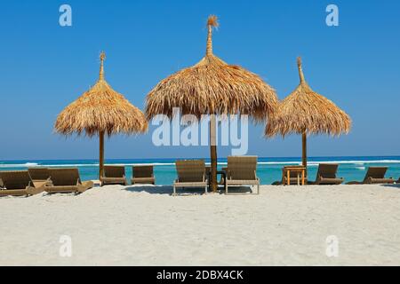 Reetgedeckte Farbtöne auf einer malerischen tropischen Insel Strand, Bali, Indonesien Stockfoto