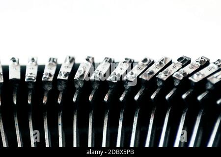 Das Eisen hämmert mit den Buchstaben, die in einer alten Schreibmaschine eingeprägt sind. Mechanische Werkzeuge zum Schreiben. Journalismus der alten Zeit Stockfoto