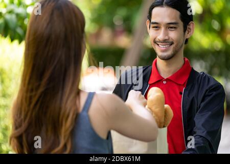 Lieferung Asian Fahrrad Mann abholen Bäckerei Lebensmittelgeschäft Tasche von Bäckerei-Shop zu Kunden, die Online-Bestellung zu liefern. Food Delivery Service Konzept in New Stockfoto