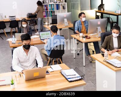 Gruppe von interracial Business Worker Team tragen schützende Gesichtsmaske in neuen normalen Büro mit sozialen Abstand Praxis mit Hand Desinfektionsmittel Alkohol Gel Stockfoto