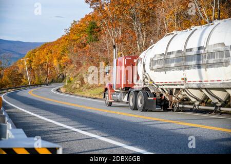 Brown klassischen Motorhaube Industrie leistungsstarke große Rig semi-Truck-Traktor Mit rundem Bulk-Sattelauflieger geht es bergab auf der Wicklung Herbststraße mit gelber und Stockfoto