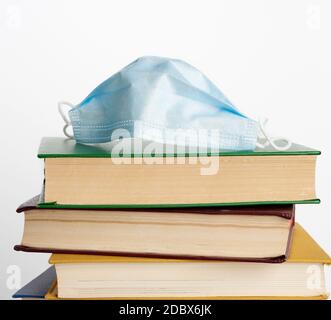 Stapel von verschiedenen Büchern und Einweg-medizinische Masken auf weißem Hintergrund, Konzept des Besuchs Bibliotheken in persönlichen Schutzausrüstung während quara Stockfoto