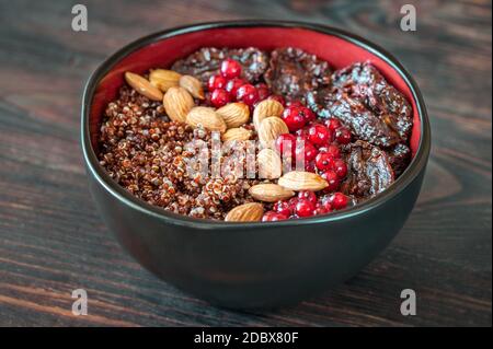 Schüssel mit roten Quinoa mit Oliven, getrockneten Tomaten, Beeren und Nüssen Stockfoto