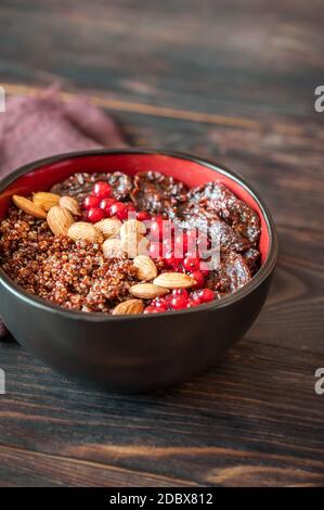 Schüssel mit roten Quinoa mit Oliven, getrockneten Tomaten, Beeren und Nüssen Stockfoto