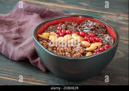 Schüssel mit roten Quinoa mit Oliven, getrockneten Tomaten, Beeren und Nüssen Stockfoto