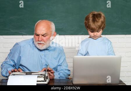 Lehrer hilft Kindern bei ihren Hausaufgaben im Klassenzimmer in der Schule. Papa Sohn sind auf das Problem konzentriert. Großvater und Enkel. Nachhilfe. Stockfoto